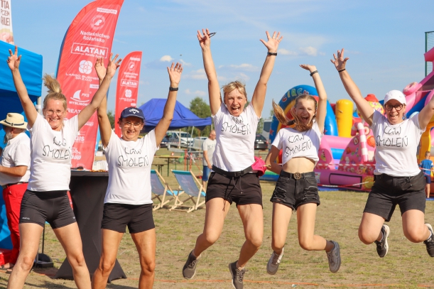 na zdjęciu widać 5 uśmiechnietych kobiet, wykonują podskok z rekoma uniesionymi do góry. Ubrane są w białe koszulki z napisem kgw smoleń